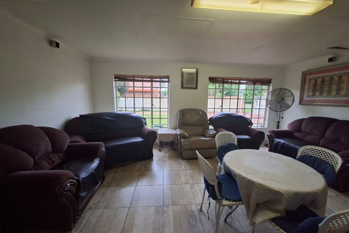 A spacious living area featuring tiled flooring and large steel-framed windows, offering a functional layout ready for modernization and aesthetic updates.