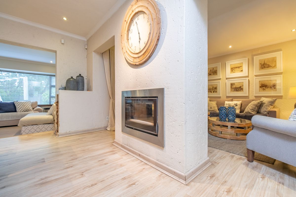 A well-maintained living area featuring a modern built-in fireplace, recessed downlights, and light-toned laminate flooring, creating a warm and inviting atmosphere.