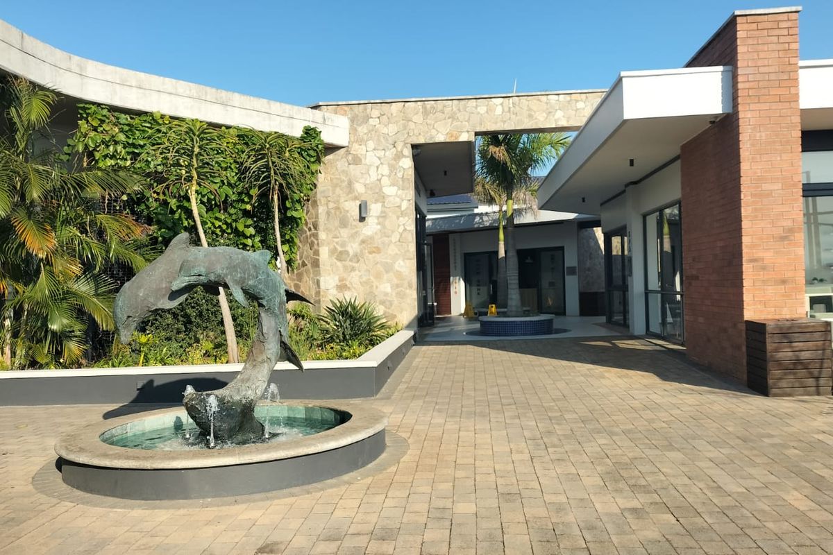 A well-maintained outdoor courtyard featuring stone and brick architectural elements, a central dolphin water feature, and paved walkways.