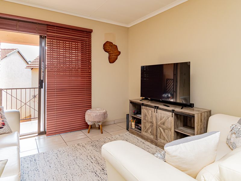 A living room featuring tiled flooring and a sliding glass door leading to a balcony, with visible wall surface imperfections requiring attention.