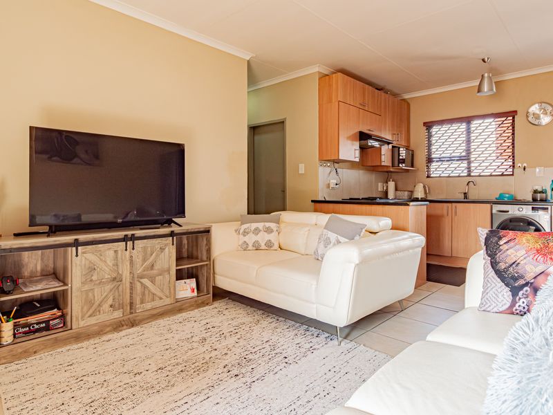 An open-plan living area featuring a functional kitchen with built-in cabinetry and tiled flooring, seamlessly connected to the lounge space.