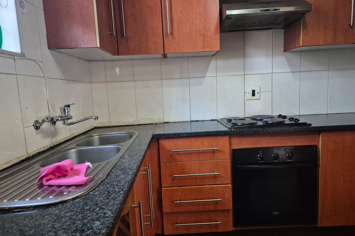 A functional kitchen featuring laminate cabinetry, granite countertops, a double bowl sink, and built-in cooking appliances with a tiled backsplash.