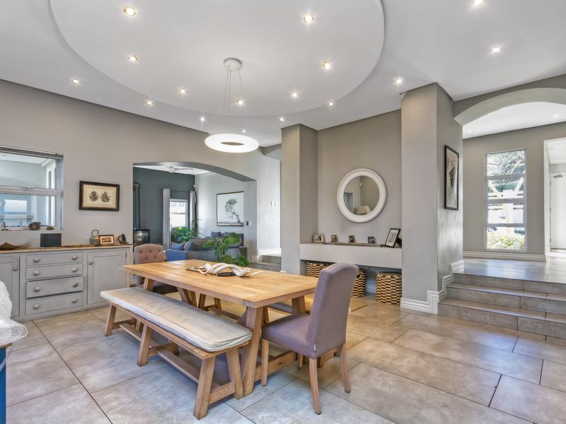 Spacious dining area featuring a unique circular ceiling design with recessed lighting, tiled floors, and an elegant archway leading to adjacent living spaces.