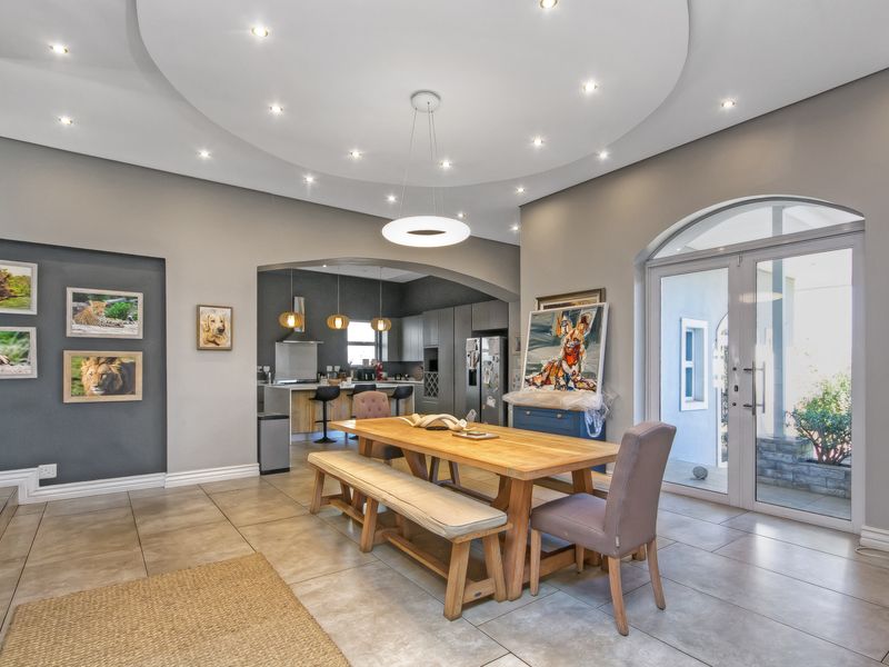 Spacious open-plan dining and kitchen area featuring modern tiled floors, recessed ceiling lighting, and an elegant archway connecting the two functional living spaces.
