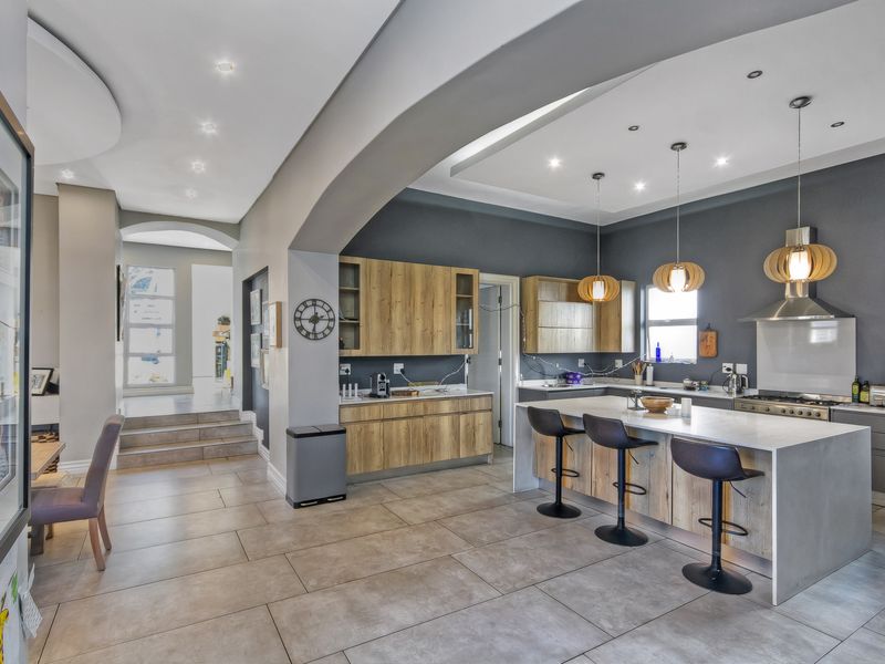 Modern open-plan kitchen featuring a large central island, stone countertops, wood-finish cabinetry, and high-end integrated appliances, seamlessly connected to the living area.