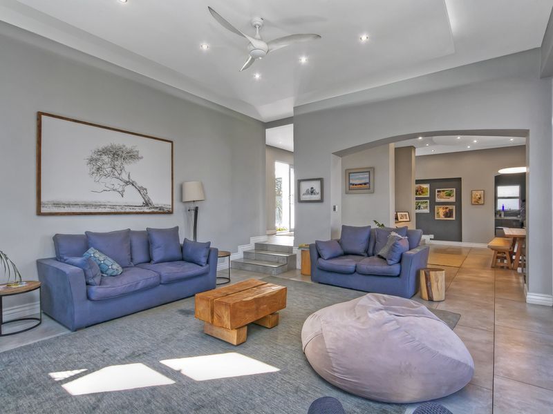 Spacious living room featuring a recessed ceiling with a fan, tiled flooring, and an elegant archway leading to the dining area.