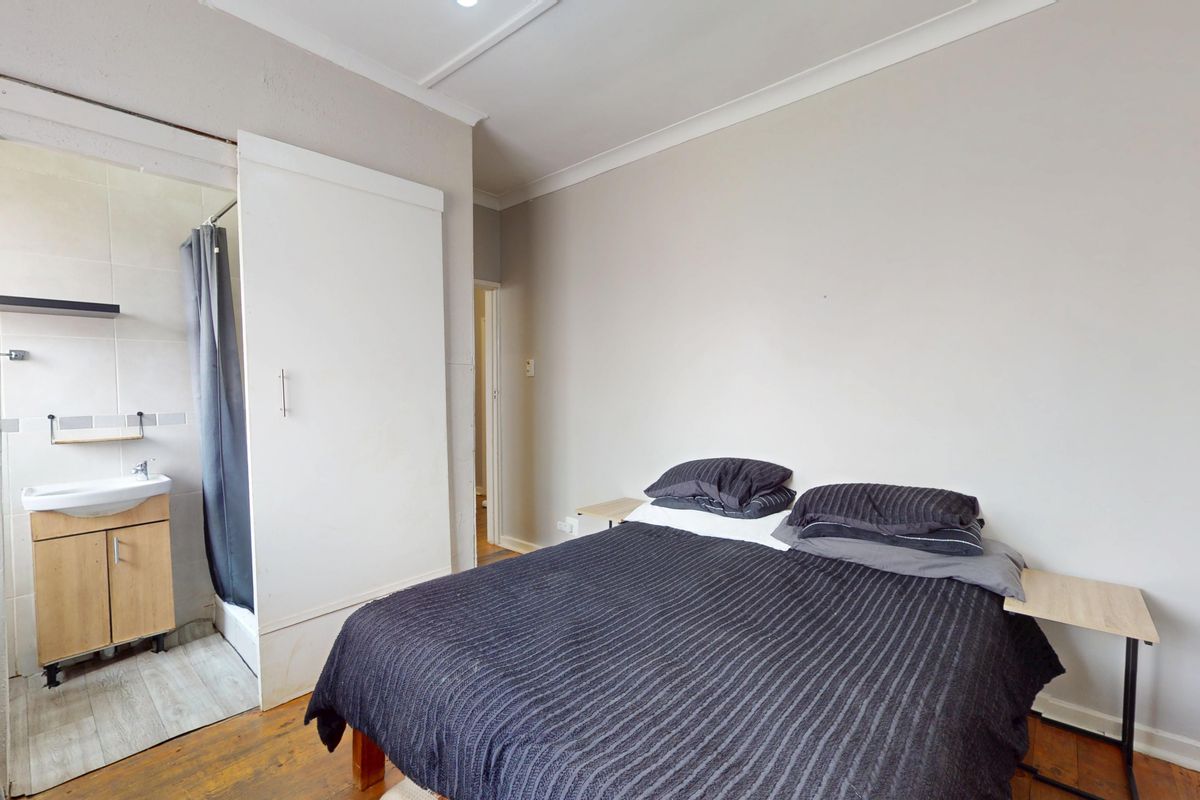 Bedroom featuring timber flooring, cove cornicing, and an integrated en-suite bathroom with a built-in vanity and shower.
