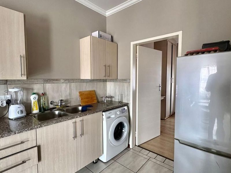 A functional kitchen featuring light wood-grain cabinetry, granite countertops, a double stainless steel sink, and an integrated space for a washing machine.