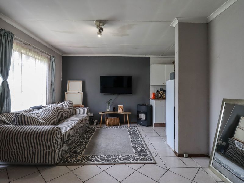 Open plan living area featuring tiled flooring and a compact kitchen corner, showing signs of ceiling water damage requiring maintenance.