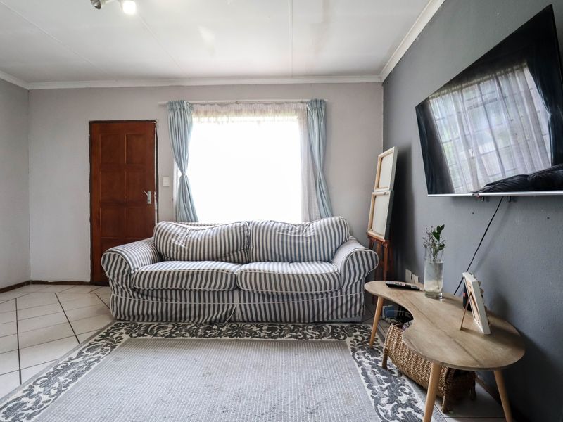 A living room featuring tiled flooring and a neutral color palette, providing a functional space with potential for modern updates.