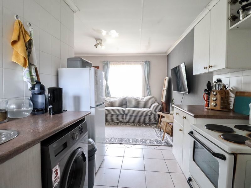 Open-plan kitchen and living area featuring tiled flooring, built-in cabinetry, and an electric stove, showing signs of ceiling water damage.