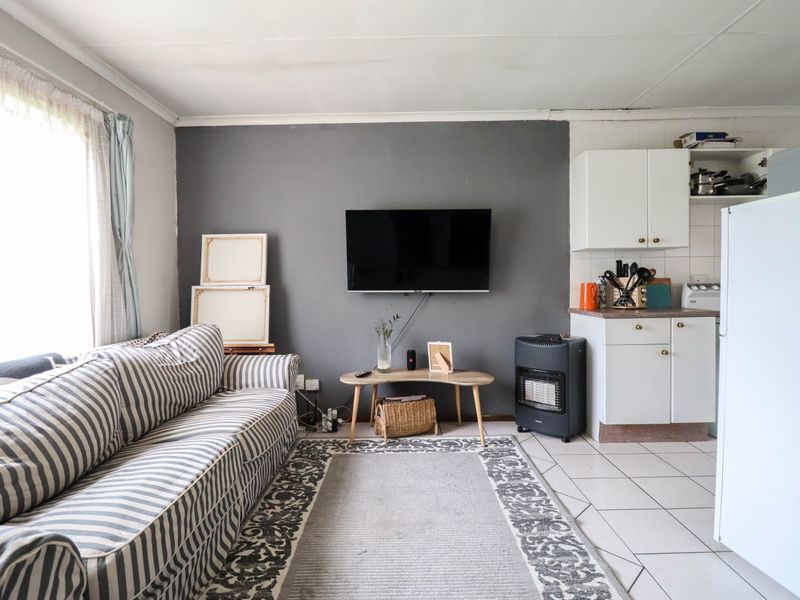 Open-plan living area featuring tiled flooring and a compact kitchen corner with built-in cabinetry.
