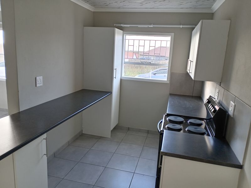 A functional kitchen featuring tiled flooring, built-in cabinetry, dark laminate countertops, and a freestanding electric stove.