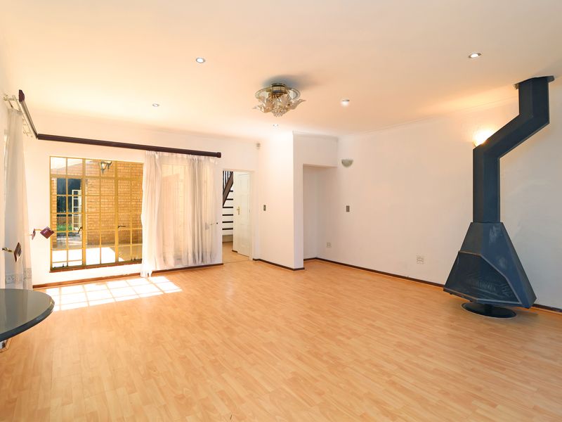 Spacious living area featuring light wood-look flooring, recessed ceiling lighting, and a prominent black metal freestanding fireplace.
