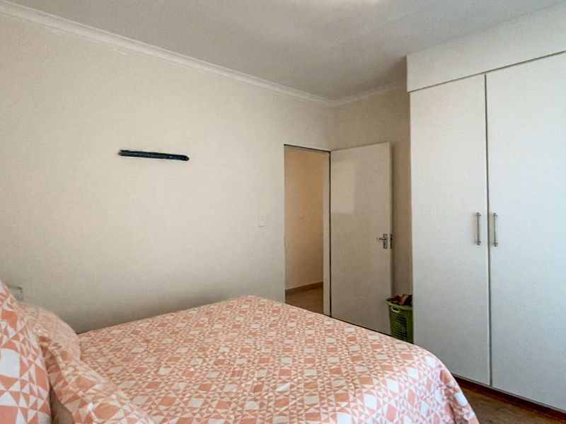 A functional bedroom featuring built-in wardrobes and neutral wall finishes, providing a clean and simple space.