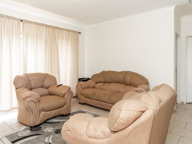 A bright living room featuring neutral tiled flooring and access to an adjacent room, providing a clean canvas for modern interior updates.