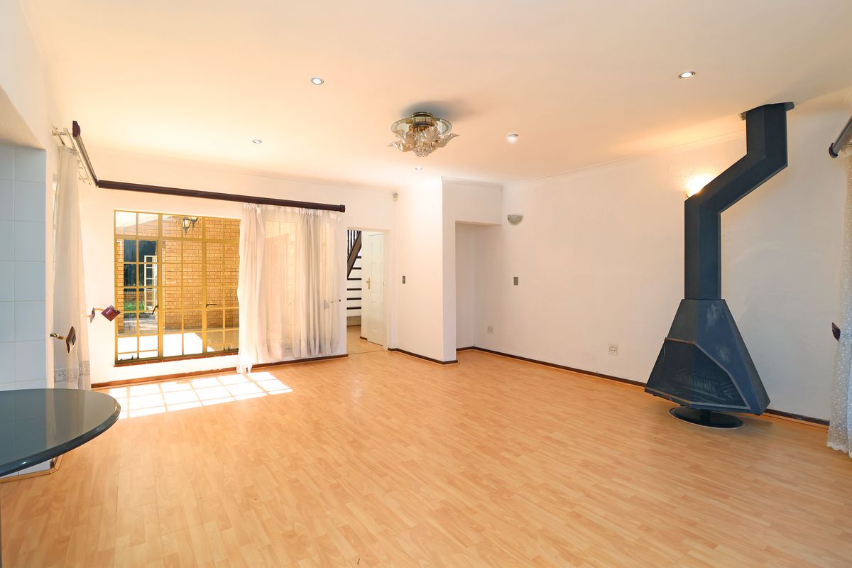 Spacious living area featuring light wood-look flooring, recessed ceiling lighting, and a prominent black metal freestanding fireplace.