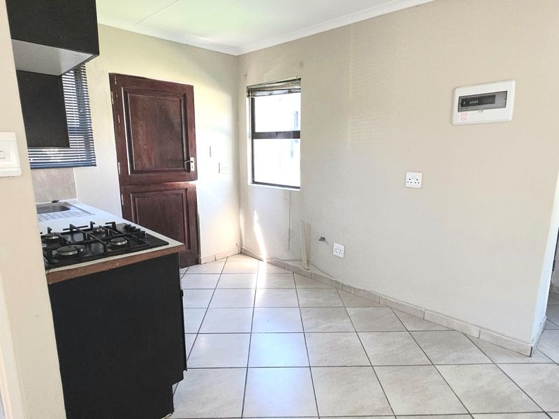 A functional kitchen area featuring tiled flooring, a gas hob with extractor, and direct access to an exterior door.