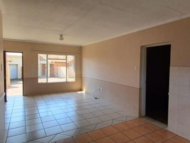 Open-plan living and kitchen area featuring tiled flooring, built-in cabinetry, and natural light, offering a functional space ready for modernization.