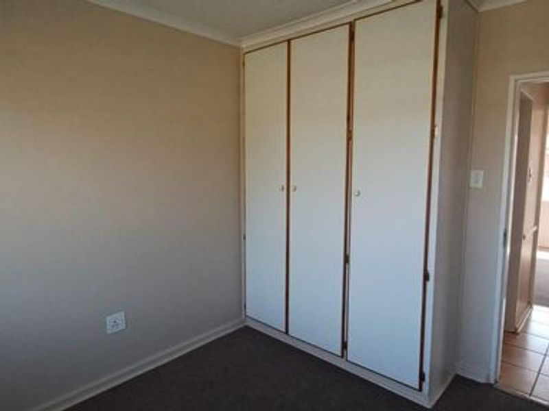 A clean, empty bedroom featuring built-in cupboards and neutral wall finishes, offering a blank canvas for personalization.