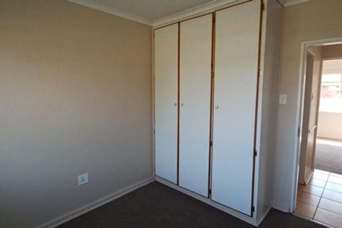 A clean, empty bedroom featuring built-in cupboards and neutral wall finishes, offering a blank canvas for personalization.