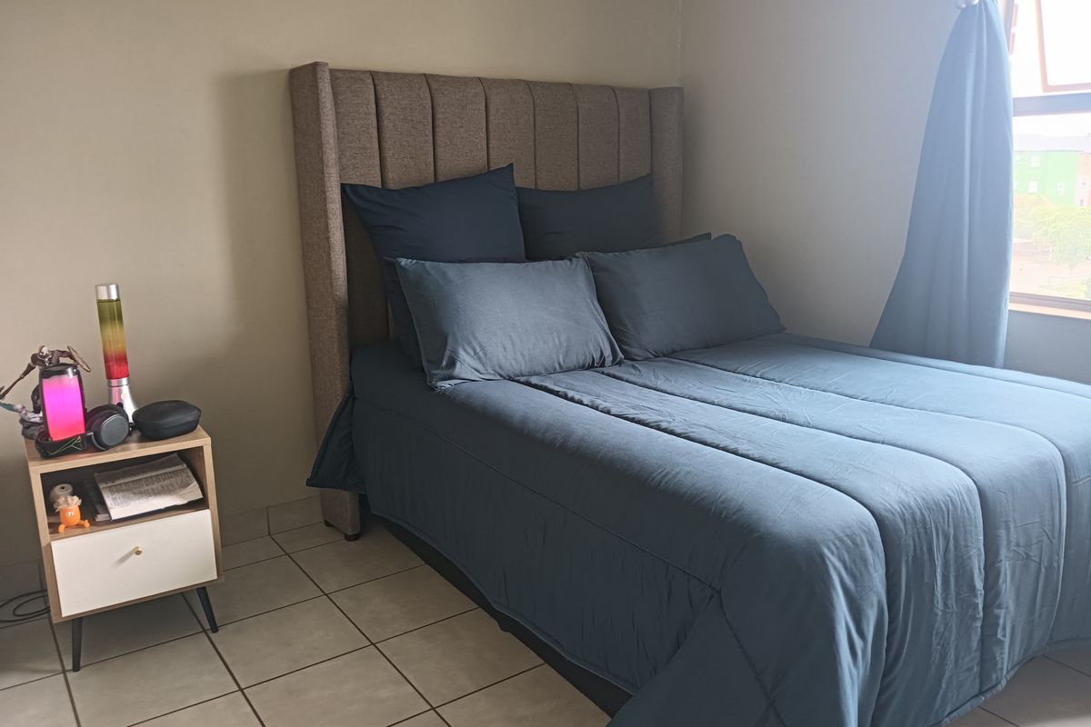 A bedroom featuring tiled flooring and a window with curtains.