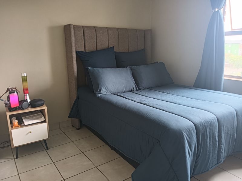 A bedroom featuring tiled flooring and a window with curtains.