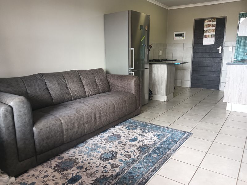 Open plan living area featuring tiled flooring and a functional kitchen space with built-in cabinetry and hob.