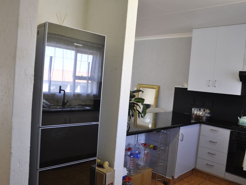 A functional kitchen featuring white cabinetry, black countertops, a built-in oven, and a dedicated alcove for a refrigerator.