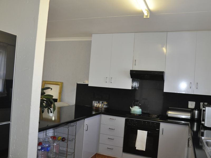 A functional kitchen featuring white cabinetry, black countertops, a built-in oven, and an extractor fan, offering a clean and practical workspace.
