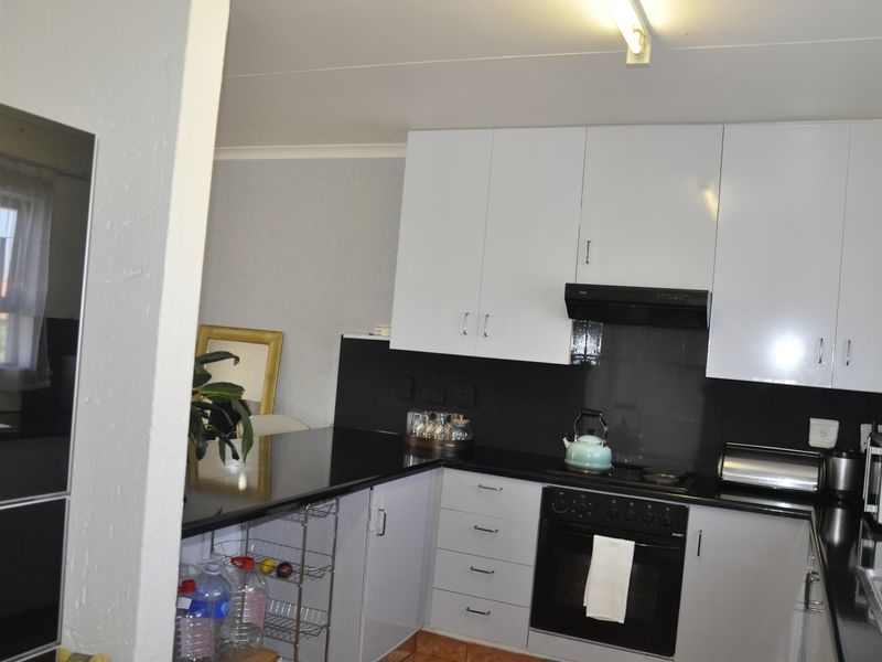 A functional kitchen featuring white cabinetry, black countertops, a built-in oven, and a black extractor fan.