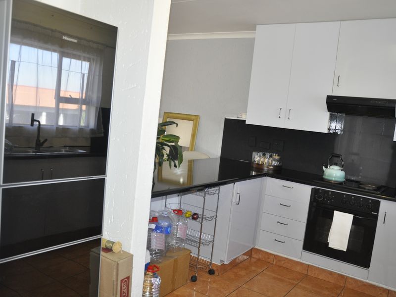 A functional kitchen featuring white upper cabinetry, dark countertops, a built-in oven with extractor fan, and tiled flooring.