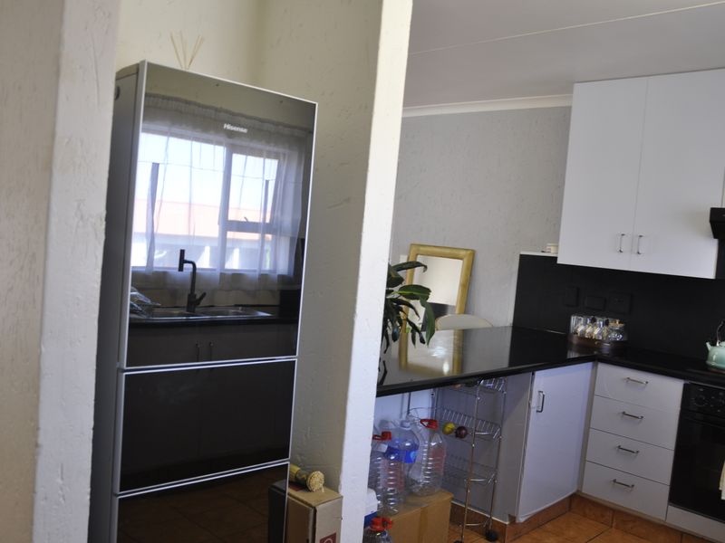 A functional kitchen featuring white cabinetry, black countertops, a built-in oven, and a black extractor fan, with a tiled floor.