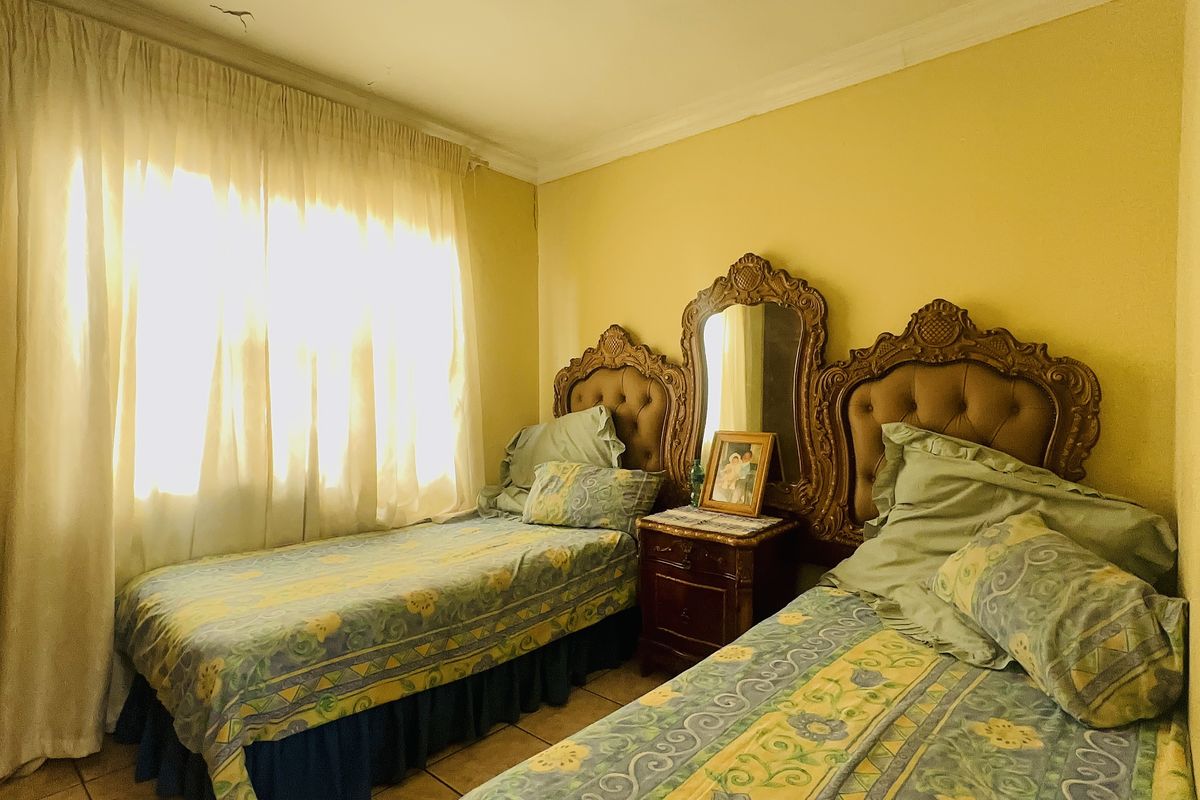 A bedroom featuring tiled flooring and coving, currently configured with twin beds.
