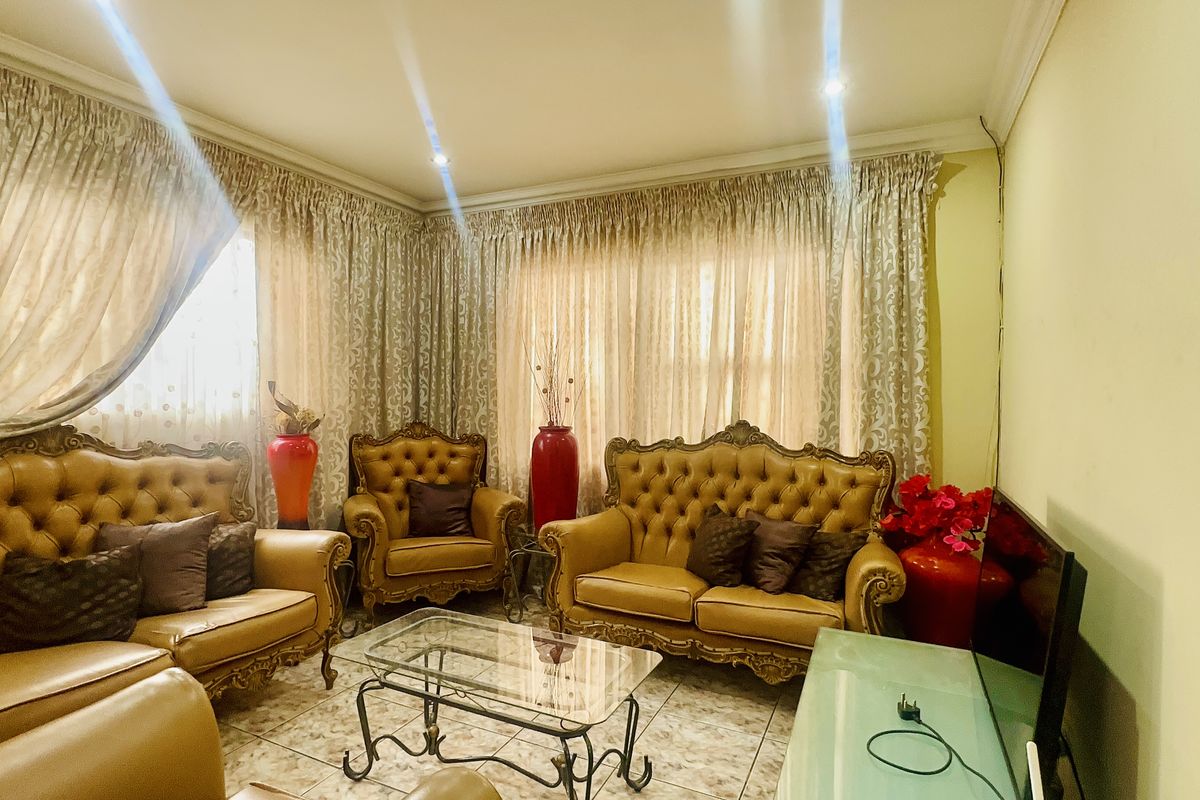 A comfortable living room featuring tiled flooring, recessed downlighting, and decorative cornicing, providing a functional space for relaxation.