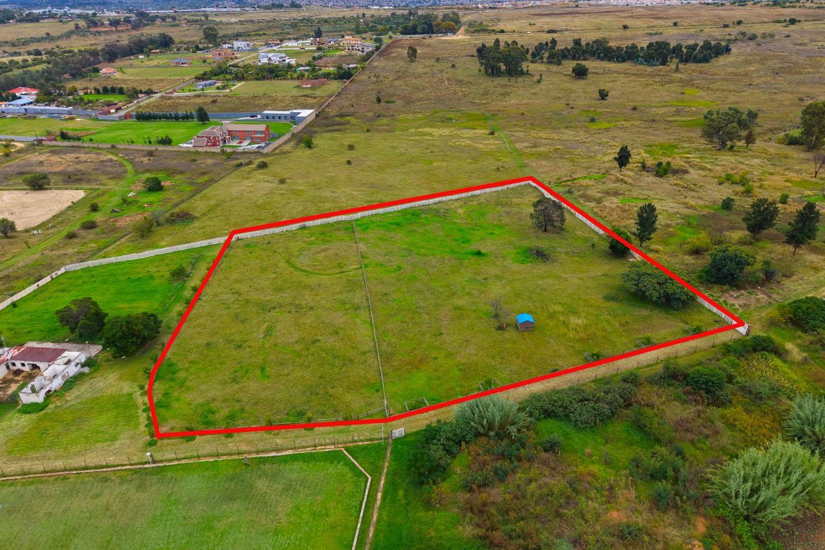 Aerial view of a vacant residential plot with clear boundary markings, situated in a developing semi-rural area.