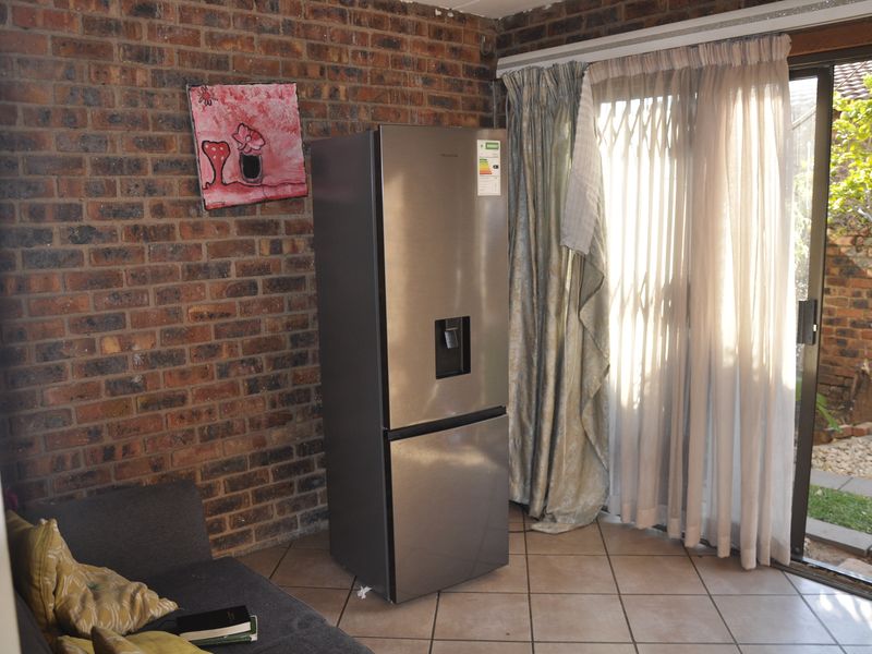 Living area featuring an exposed brick wall, ceramic floor tiles, and a sliding glass door providing access to the rear garden.