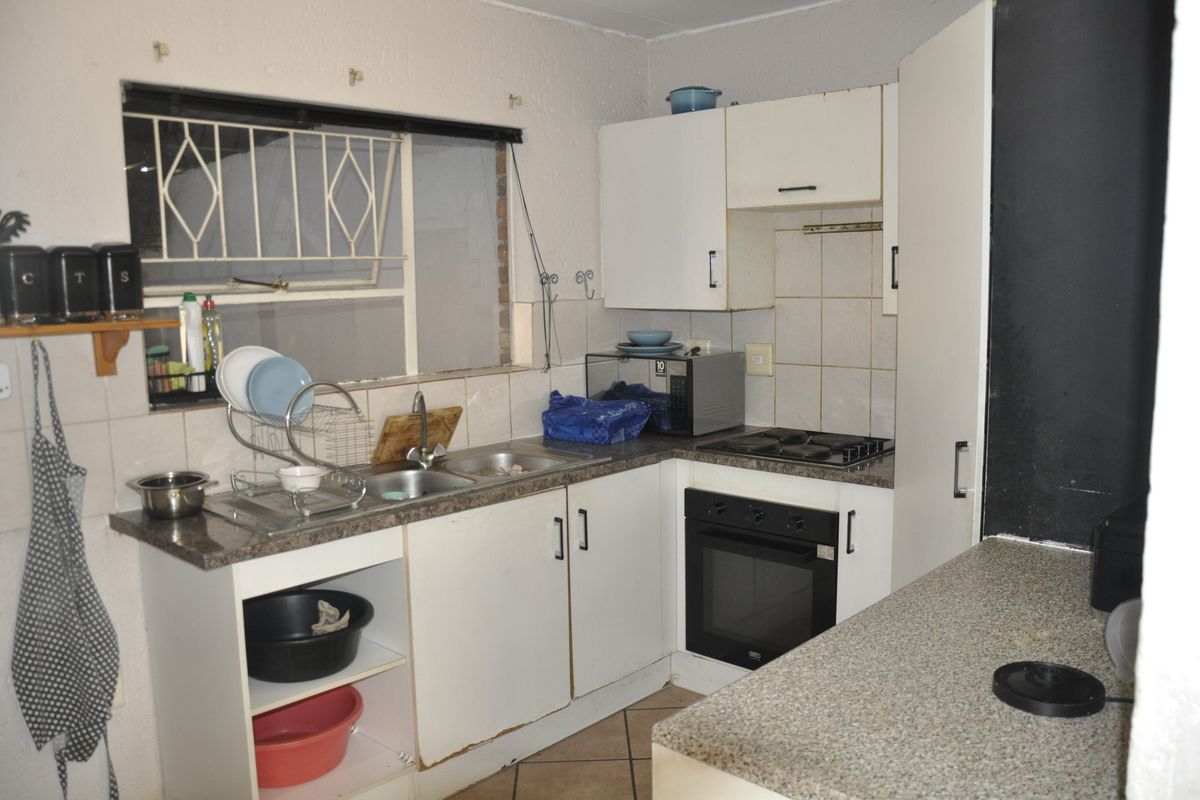 Compact kitchen featuring built-in cabinetry, laminate countertops, a stainless steel sink, and integrated oven and hob, requiring cosmetic updates to improve functionality and aesthetic appeal.