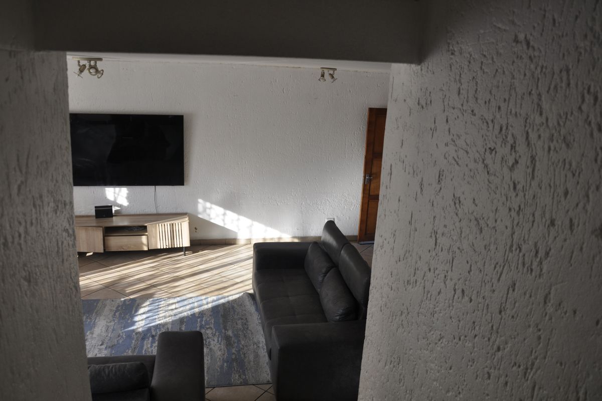 A view into a living room featuring tiled flooring and textured walls, captured from an adjacent space.