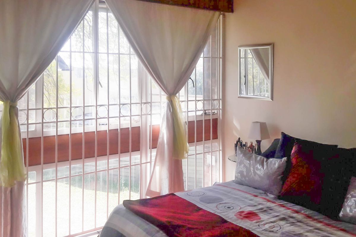 A bedroom featuring large windows with integrated security bars, providing natural light and a view of the exterior.