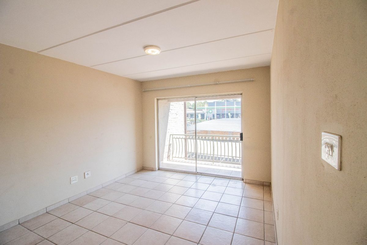 An empty living room featuring tiled flooring and a sliding glass door that provides access to a balcony.