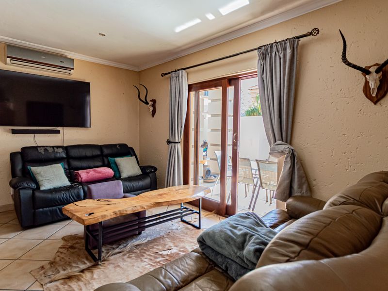 A living room featuring tiled flooring, a split-system air conditioner, and a sliding glass door providing access to an outdoor patio area.