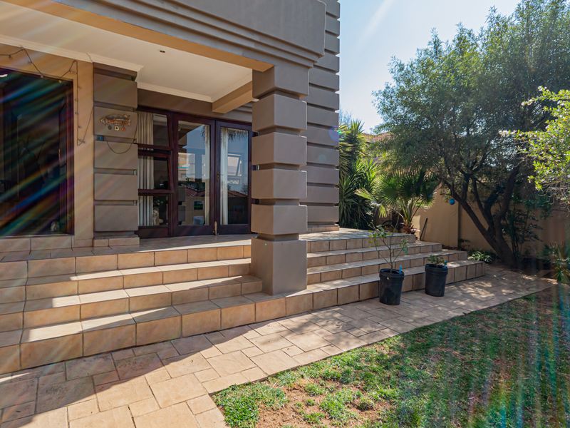A rear exterior view of the townhouse featuring a tiled patio area, concrete pillars, and sliding glass doors leading into the home.