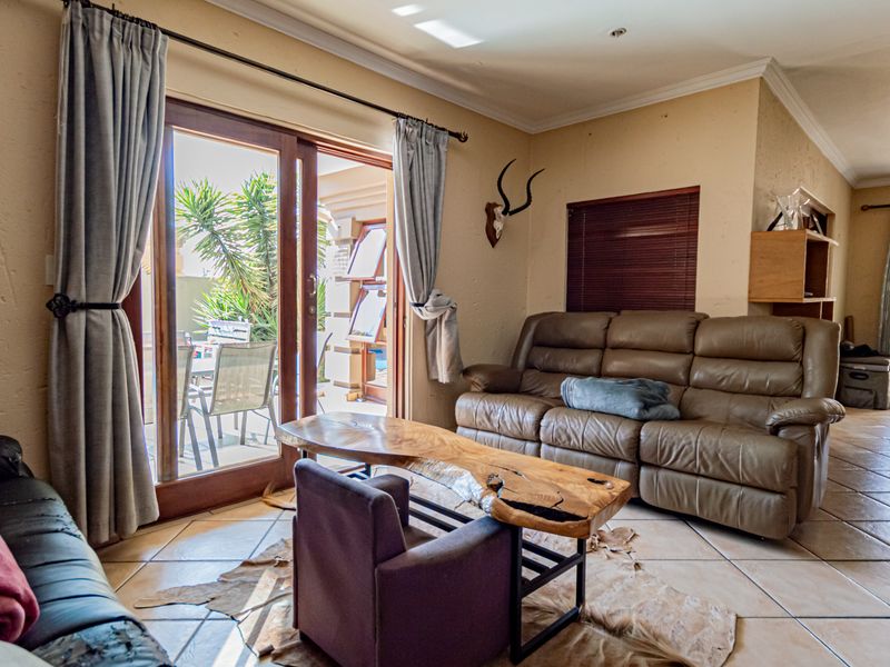 A living room featuring tiled flooring, crown molding, and a sliding glass door providing direct access to the outdoor patio area.