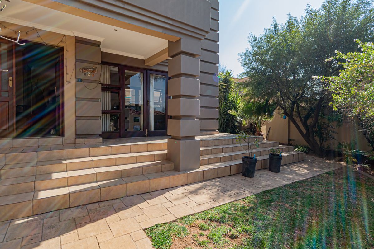 A rear exterior view of the townhouse featuring a tiled patio area, concrete pillars, and sliding glass doors leading into the home.