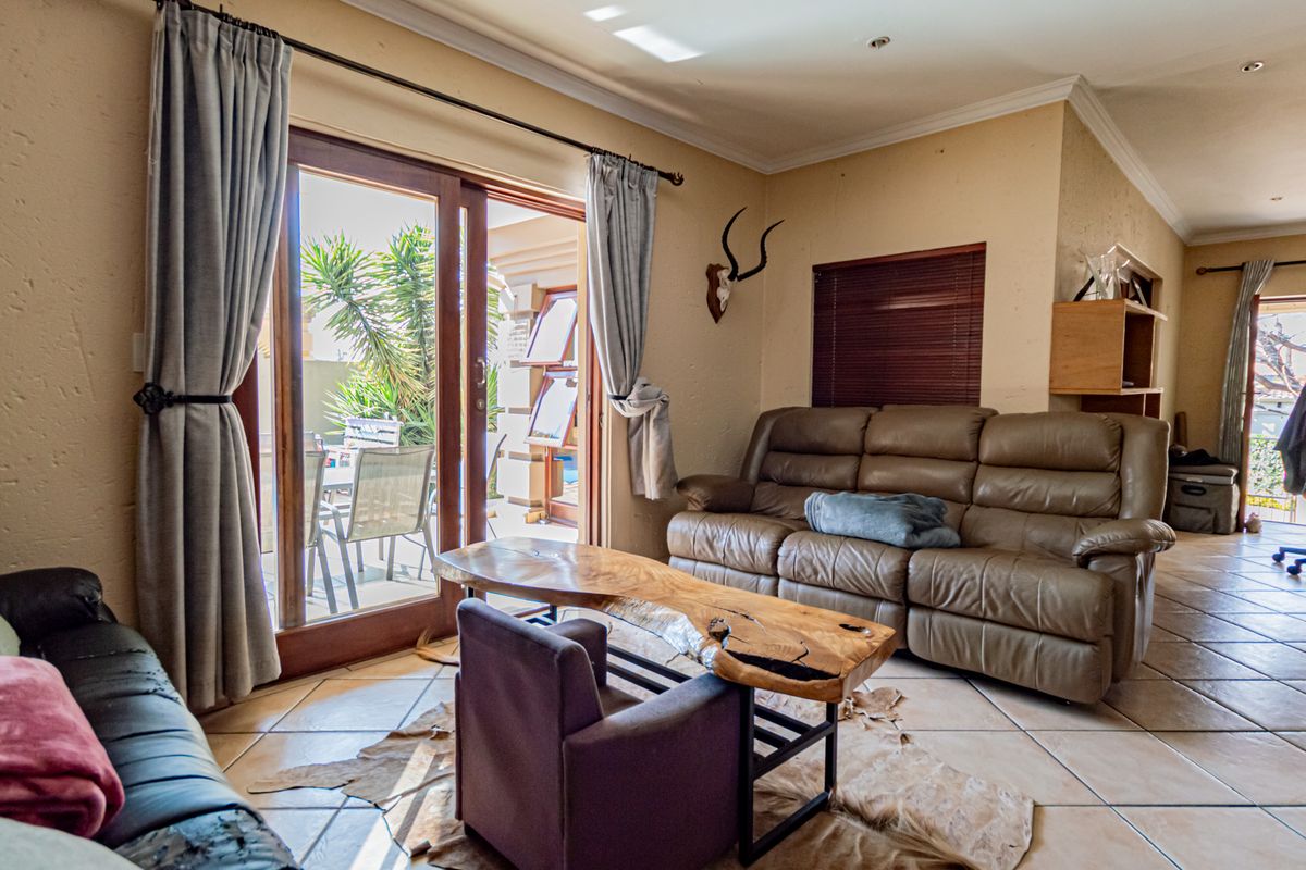A living room featuring tiled flooring, crown molding, and a sliding glass door providing direct access to the outdoor patio area.