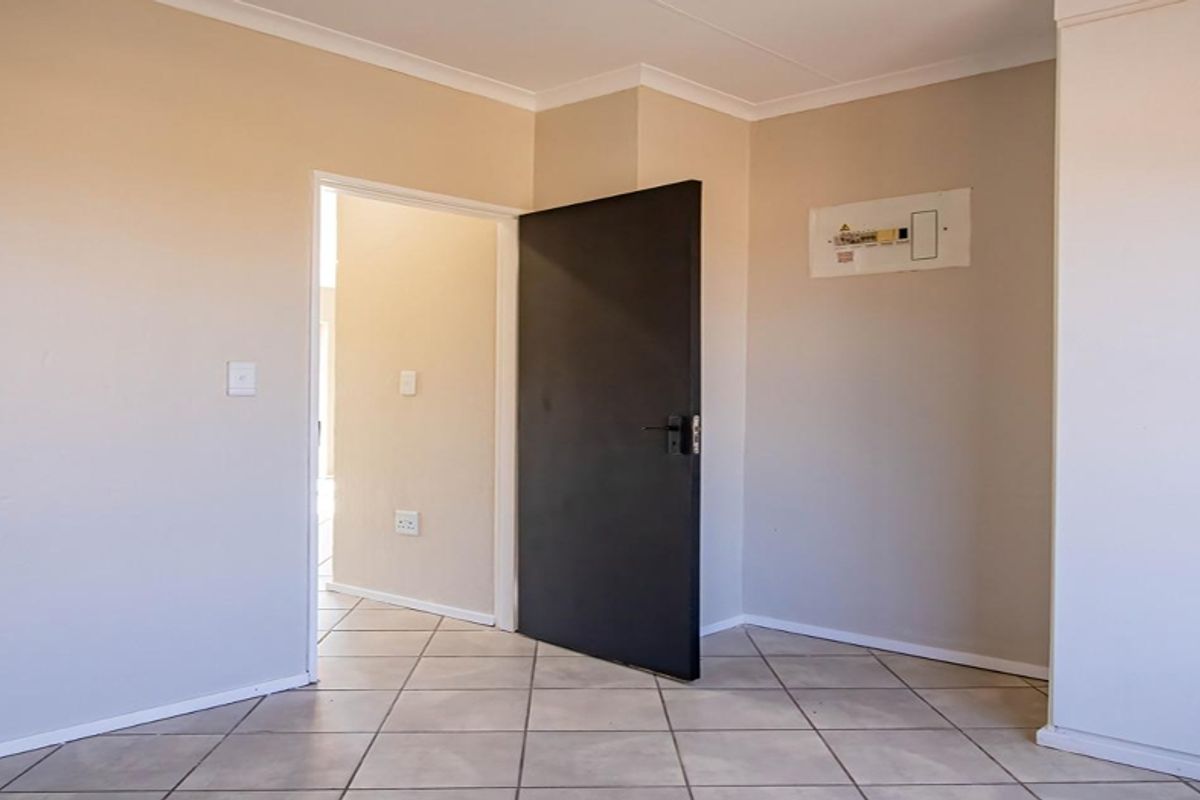 An empty bedroom featuring neutral wall finishes, tiled flooring, and a built-in cupboard with a visible electrical distribution board.