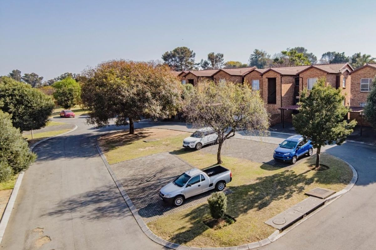 Aerial view of the apartment complex exterior, featuring brick facades, tiled roofing, and paved parking areas within a landscaped residential setting.