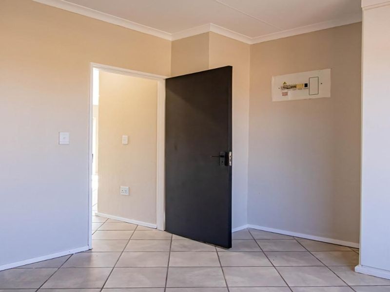 An empty bedroom featuring neutral wall finishes, tiled flooring, and a built-in cupboard with a visible electrical distribution board.
