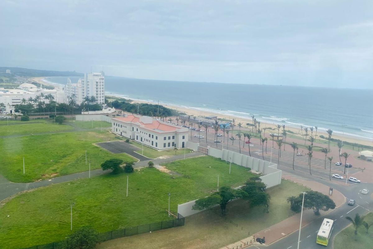 Elevated aerial view overlooking the coastal landscape, beach, and surrounding urban infrastructure.